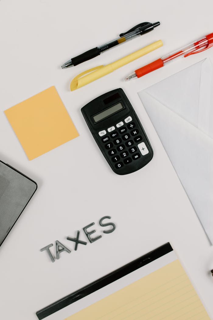 The Correct Way a Single-Member LLC Owner Should Fill Out a W-9 Flat lay of calculator, envelope, and stationery for tax preparation on a white background.